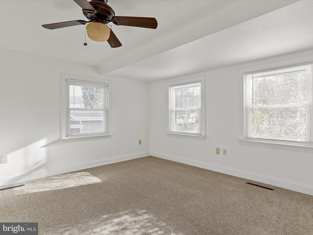 carpeted empty room with ceiling fan and plenty of natural light