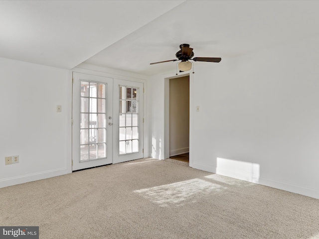 empty room featuring ceiling fan, french doors, and light colored carpet