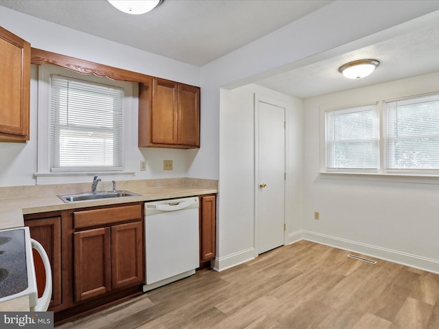 kitchen featuring dishwasher, stove, light hardwood / wood-style flooring, and sink