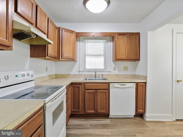 kitchen with a textured ceiling, white appliances, sink, and light hardwood / wood-style flooring