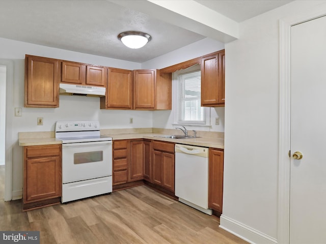 kitchen with light wood-type flooring, a textured ceiling, white appliances, and sink