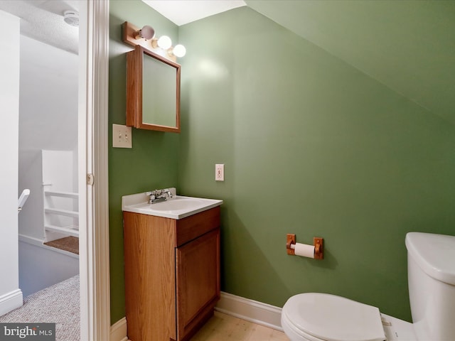 bathroom featuring vanity, lofted ceiling, and toilet