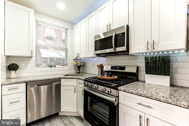 kitchen featuring light stone counters, white cabinetry, and stainless steel appliances