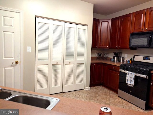 kitchen with light tile patterned flooring, sink, and stainless steel stove