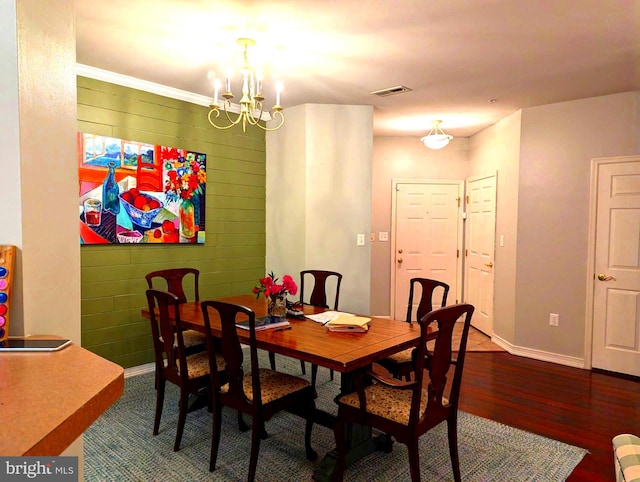 dining space with a notable chandelier, dark wood-type flooring, and wooden walls