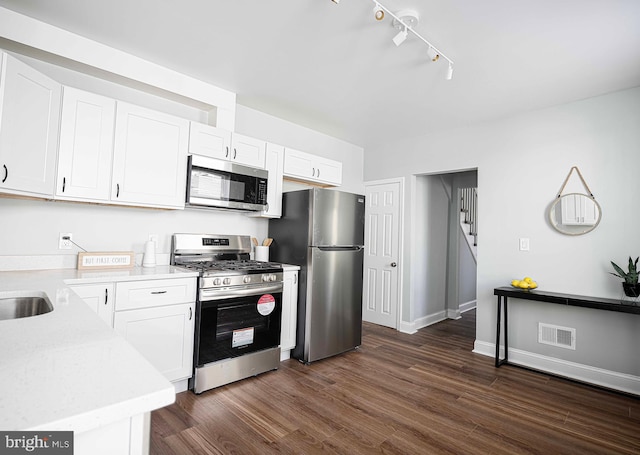 kitchen featuring white cabinets, appliances with stainless steel finishes, rail lighting, and dark hardwood / wood-style floors