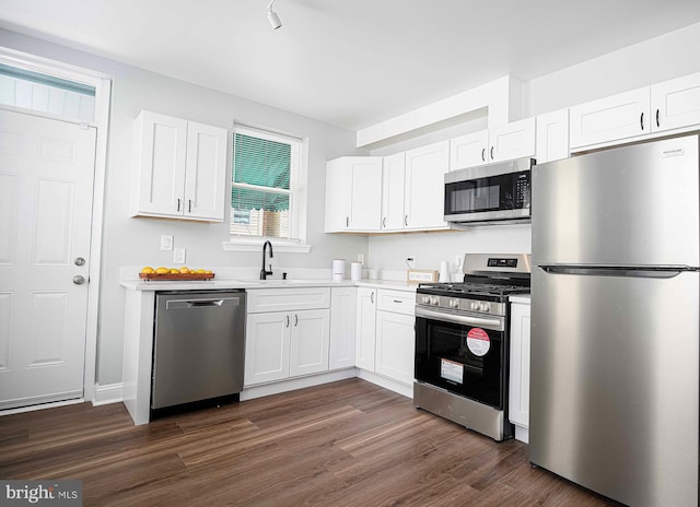 kitchen with white cabinets, appliances with stainless steel finishes, dark hardwood / wood-style flooring, and sink