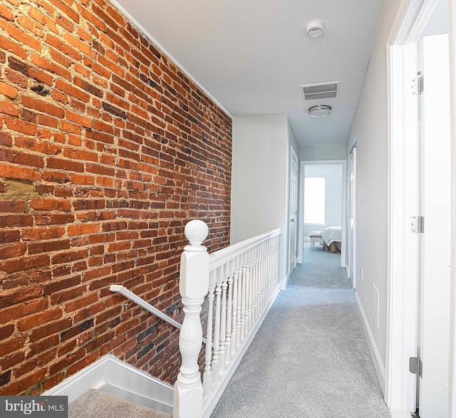 corridor with carpet floors and brick wall