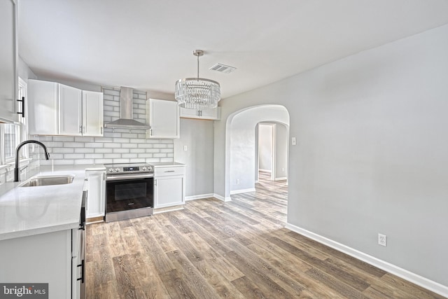 kitchen featuring white cabinetry, stainless steel electric range oven, sink, and wall chimney range hood