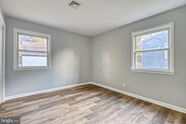 empty room with hardwood / wood-style flooring and a healthy amount of sunlight