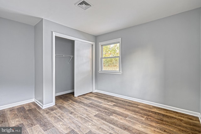 unfurnished bedroom with dark hardwood / wood-style flooring and a closet