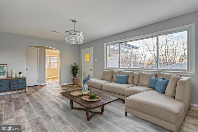 living room featuring an inviting chandelier, a wealth of natural light, and light hardwood / wood-style flooring