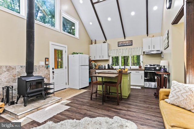 kitchen featuring stainless steel electric stove, high vaulted ceiling, white cabinets, white fridge, and a wood stove