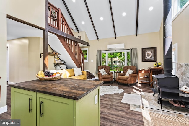 interior space with a wood stove, green cabinets, dark hardwood / wood-style flooring, high vaulted ceiling, and a kitchen island