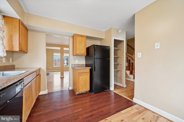 kitchen featuring black appliances, sink, and dark wood-type flooring