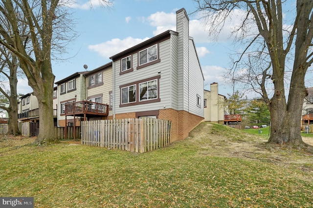 rear view of house featuring a lawn and a wooden deck