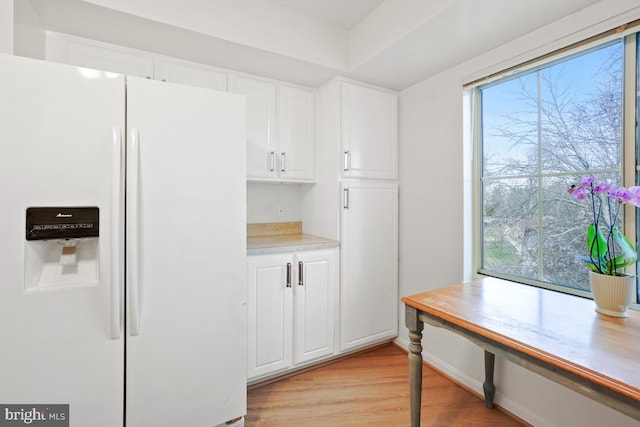 kitchen featuring white cabinets, light hardwood / wood-style floors, and white fridge with ice dispenser