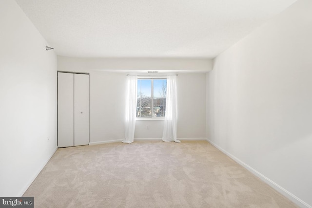 unfurnished bedroom featuring light colored carpet and a closet