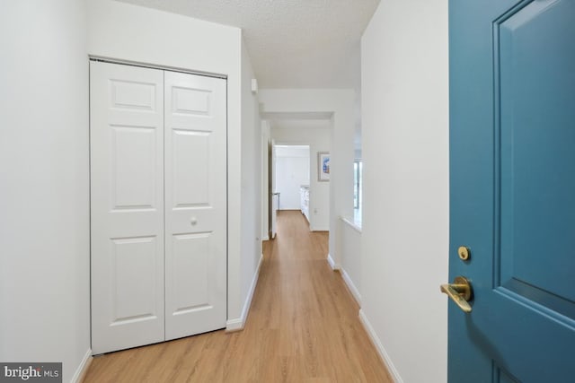 corridor featuring a textured ceiling and light wood-type flooring