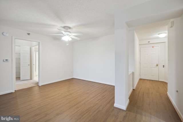 unfurnished room with ceiling fan, wood-type flooring, and a textured ceiling