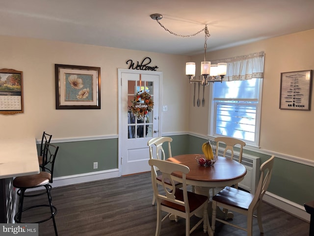 dining space with dark hardwood / wood-style floors and an inviting chandelier