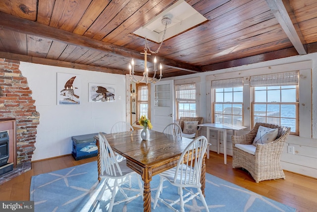 dining area with wood ceiling, a water view, light hardwood / wood-style floors, and beam ceiling