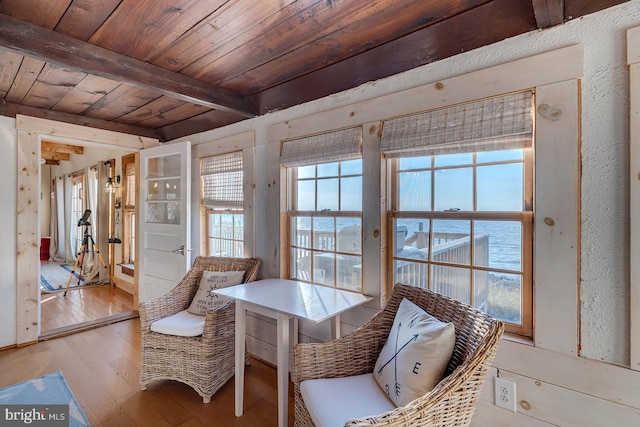 living area featuring beamed ceiling, light hardwood / wood-style floors, a water view, and wood ceiling