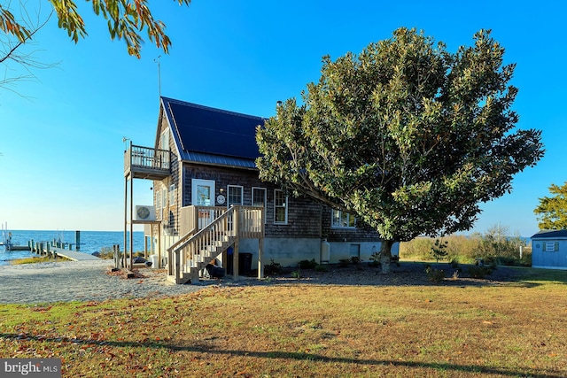 view of property exterior with a water view, a dock, and a lawn