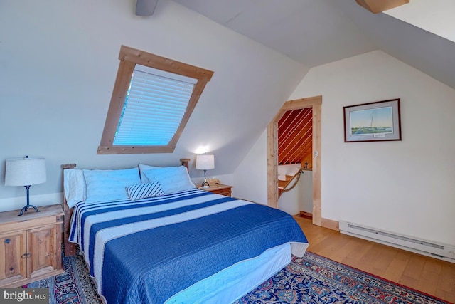 bedroom with hardwood / wood-style floors, vaulted ceiling, and a baseboard heating unit