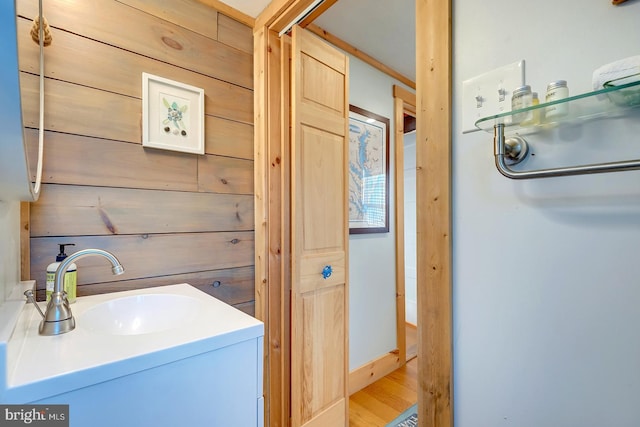 bathroom with wood walls, hardwood / wood-style floors, and vanity