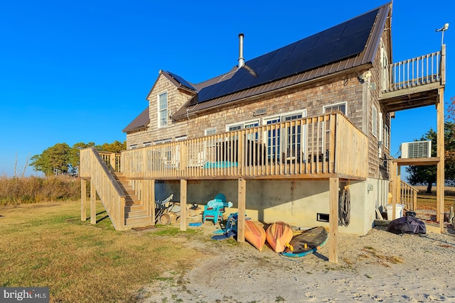 rear view of house featuring a wooden deck, a yard, and solar panels