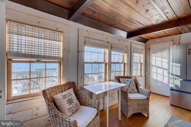 sitting room with beam ceiling, a water view, light hardwood / wood-style flooring, and wood ceiling