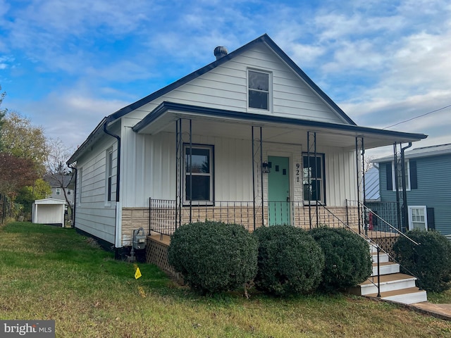 view of front of home featuring an outbuilding, a porch, and a front lawn