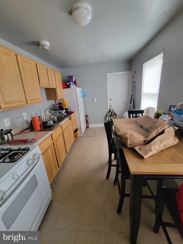 kitchen featuring light brown cabinets, white appliances, and sink