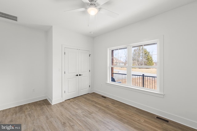 unfurnished bedroom with ceiling fan, a closet, and light wood-type flooring