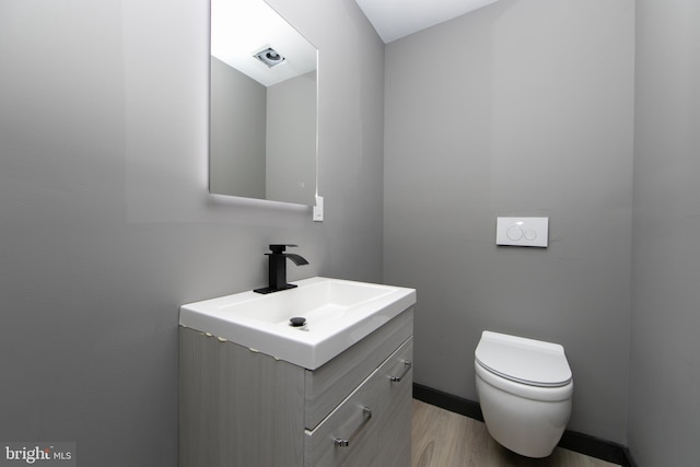 bathroom with hardwood / wood-style floors, vanity, and toilet