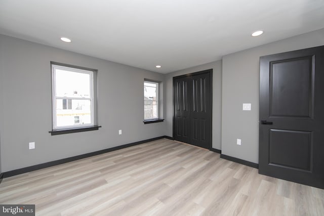 unfurnished bedroom with light wood-type flooring and a closet