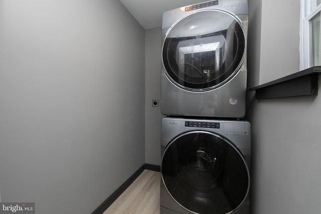 laundry room featuring stacked washing maching and dryer and light hardwood / wood-style floors