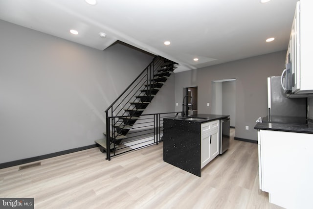 kitchen featuring white cabinetry, sink, an island with sink, light hardwood / wood-style floors, and appliances with stainless steel finishes