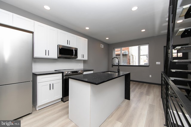 kitchen with stainless steel appliances, sink, a center island with sink, light hardwood / wood-style flooring, and white cabinets