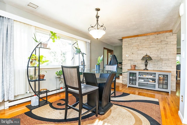 dining space with plenty of natural light, light hardwood / wood-style floors, and a baseboard heating unit