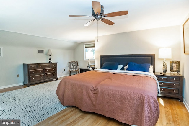 bedroom featuring light wood-type flooring, vaulted ceiling, and ceiling fan