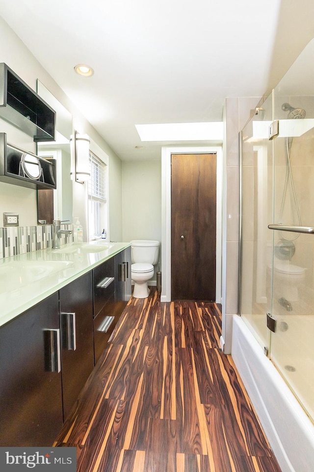 full bathroom featuring vanity, hardwood / wood-style flooring, toilet, and enclosed tub / shower combo