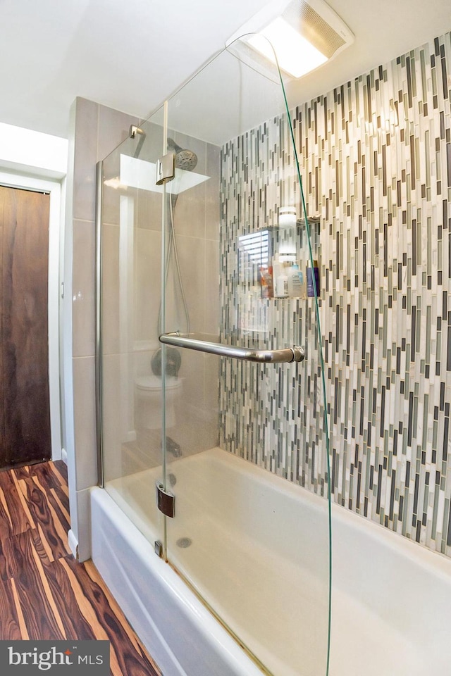 bathroom featuring hardwood / wood-style floors and bath / shower combo with glass door