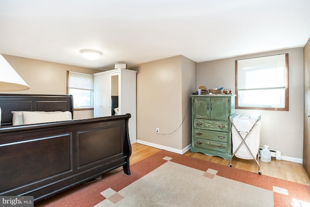 bedroom with a baseboard radiator and light hardwood / wood-style flooring