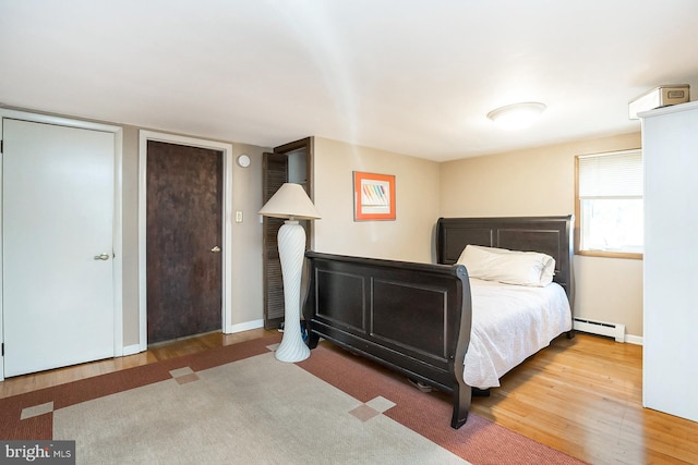 bedroom featuring hardwood / wood-style flooring and a baseboard heating unit