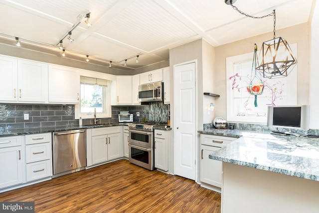 kitchen featuring dark hardwood / wood-style floors, decorative backsplash, appliances with stainless steel finishes, decorative light fixtures, and white cabinetry