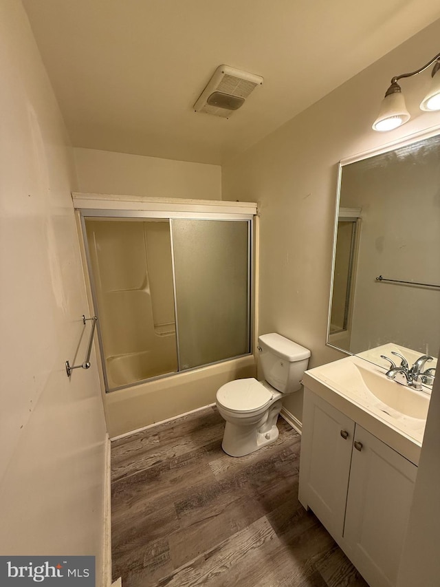 full bathroom featuring shower / bath combination with glass door, toilet, vanity, and hardwood / wood-style flooring