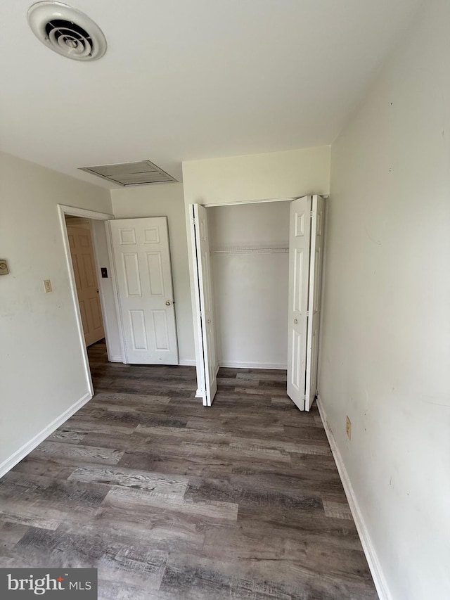 unfurnished bedroom with a closet and dark wood-type flooring