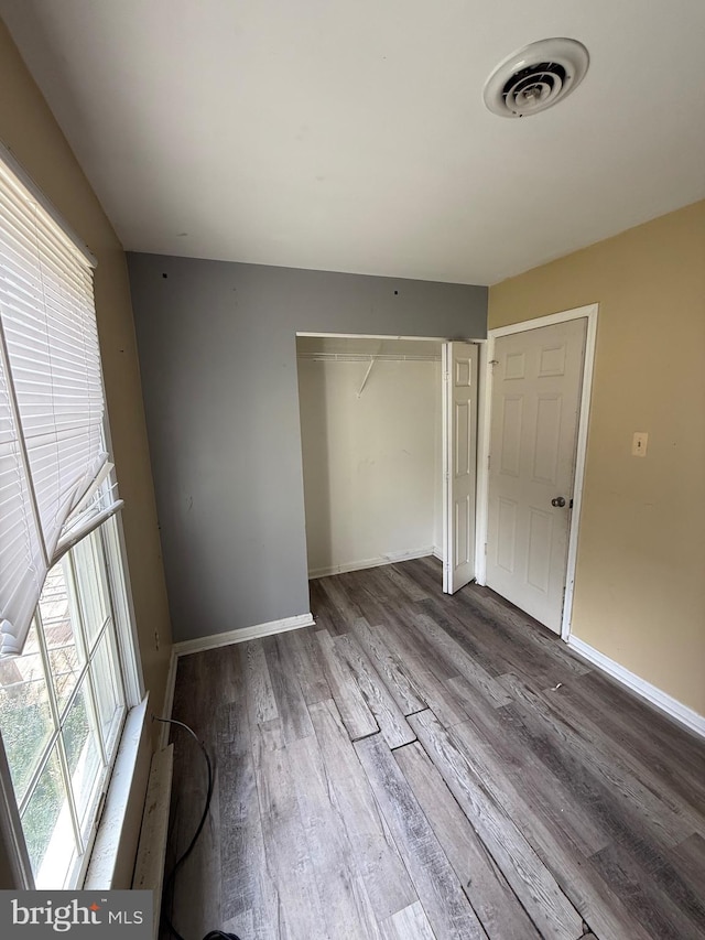 unfurnished bedroom featuring hardwood / wood-style floors and a closet